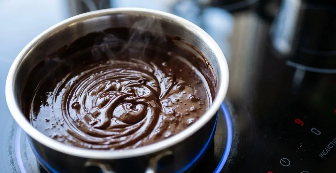 Piano a induzione con pentolino di cioccolato fuso e termometro digitale che mostra temperatura precisa