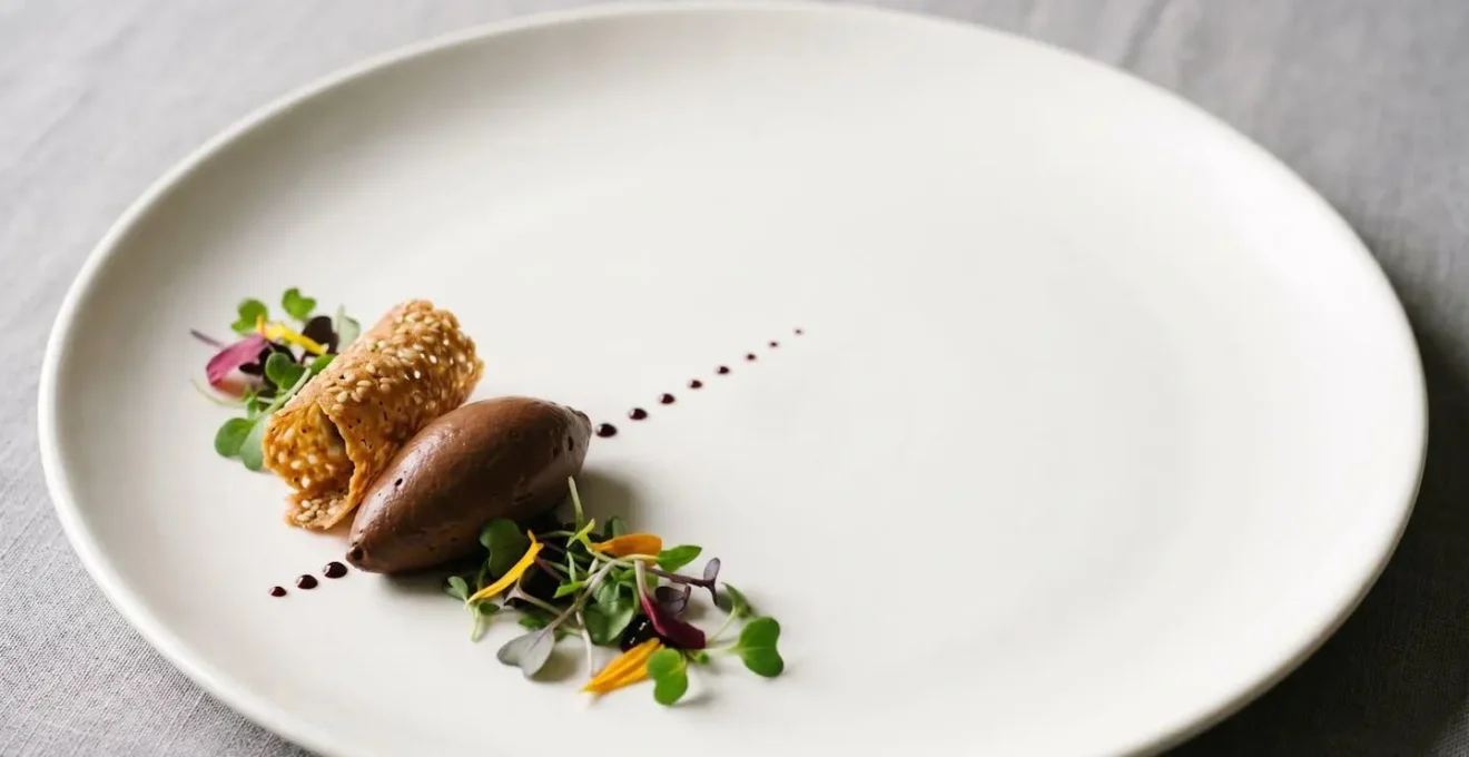 Piatto bianco con disposizione minimalista del cibo che occupa solo un terzo della superficie, mostrando l'eleganza dello spazio vuoto